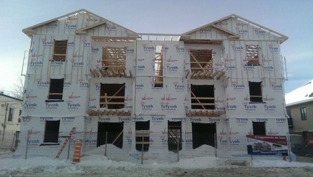 Bâtiment de logements en construction avec une structure en bois sous un paysage enneigé.
