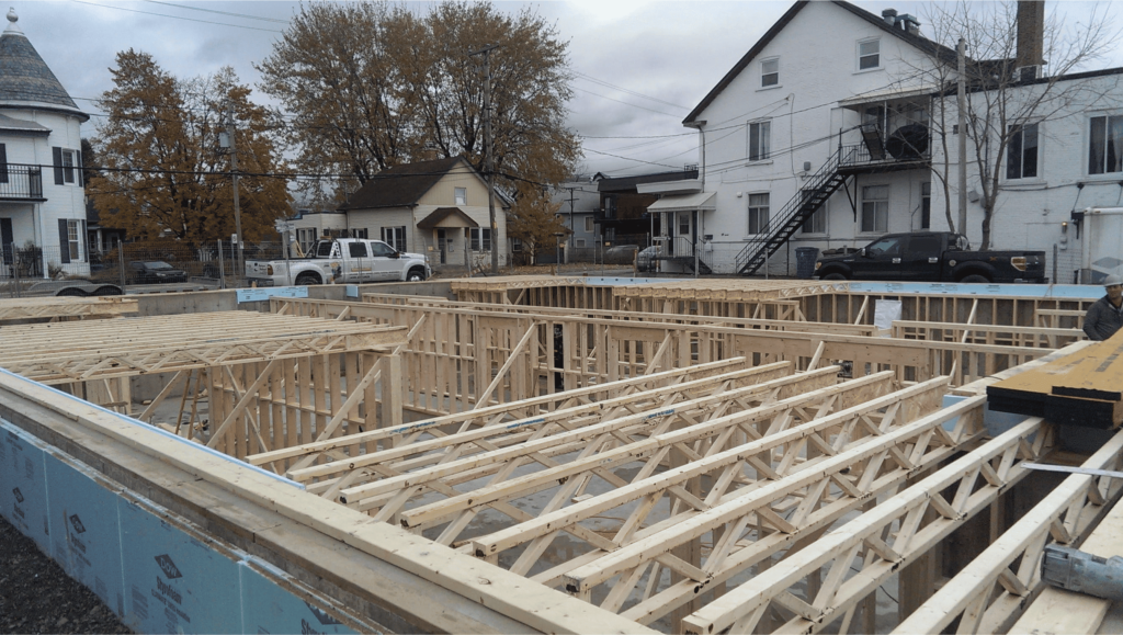 Vue d’un chantier de construction montrant l’installation des poutrelles de plancher en bois pour un bâtiment résidentiel.
