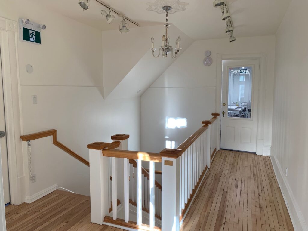 Escalier rénové avec rambarde en bois et murs blancs dans un espace intérieur lumineux.