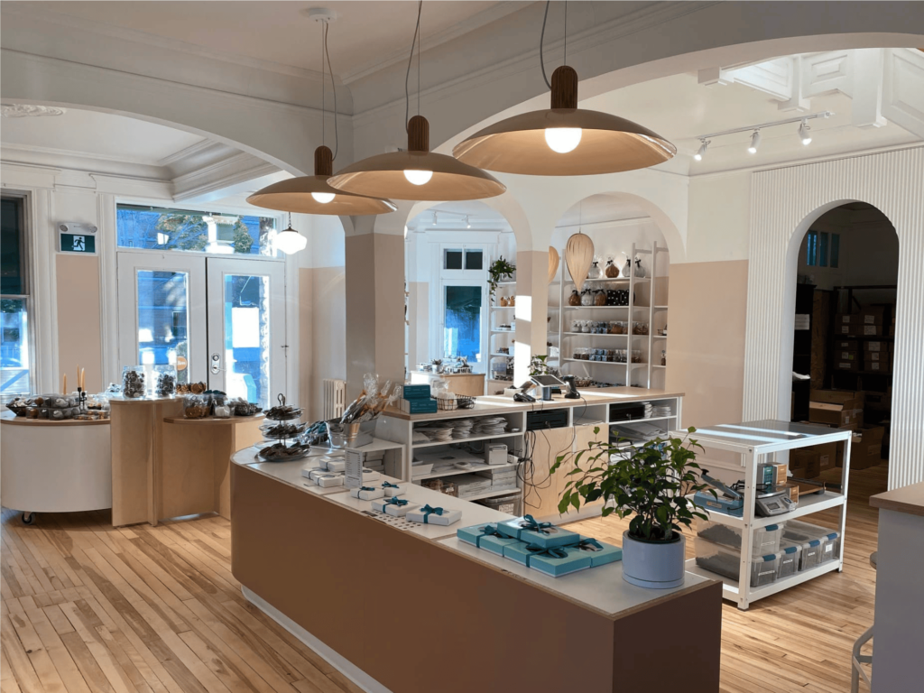 Intérieur d'une chocolaterie artisanale avec comptoir en bois, étagères remplies de chocolats et un éclairage chaleureux.