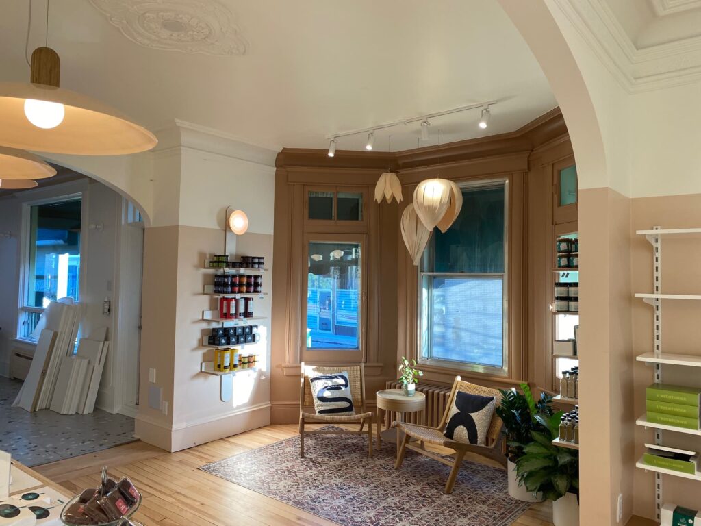 Coin détente dans une boutique rénovée avec chaises en rotin, étagères de produits et luminaires design.